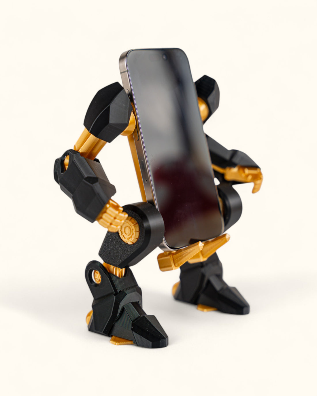 3D-printed mech-inspired phone stand with detailed armour plates, gear design, and hand feature for holding a charging cable, adjustable to fit most modern smartphones.