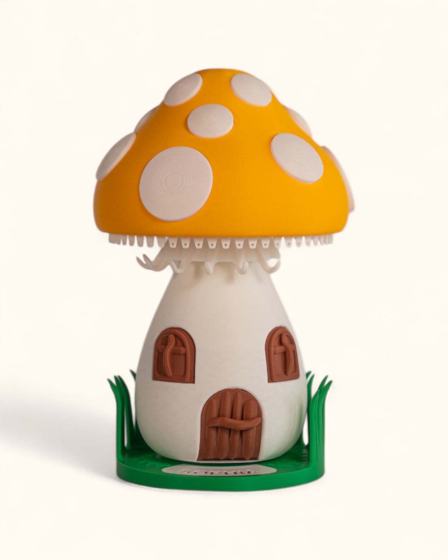 3D printed mushroom jewelry organizer with white spots, doors, windows as storage and green grass ring holder base and custom text printed on doorstep.